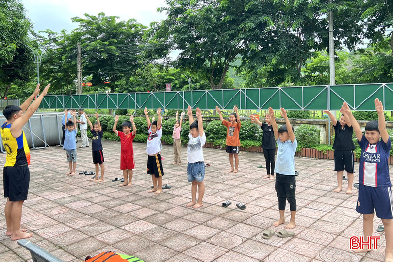 Tình nguyện viên hướng dẫn các em khởi động trước khi xuống bể bơi.