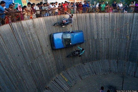 Ngày 20/6: Một nhóm thanh niên đang biểu diễn một màn lái xe nghẹt thở bên trong “Giếng Tử thần” được lợp quanh bằng những thanh gỗ tại thành phố New Delhi, Ấn Độ.