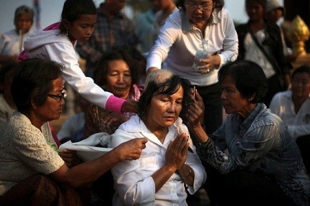 Ngày 31/1: Một người phụ nữ Campuchia đang ngồi cầu nguyện trong khi những người khác cạo đầu cho bà. Hành động này nhằm thể hiện sự thương tiếc dành cho quốc vương quá cố Norodom Sihanouk.
