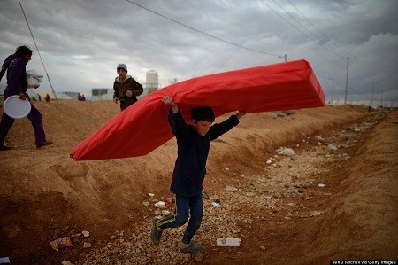 Ngày 29/1: Một cậu bé người Syria vui mừng khiêng chiếc đệm vừa được phân phát về nhà. Em đang sống trong trại tị nạn Zaatari ở Jordan.