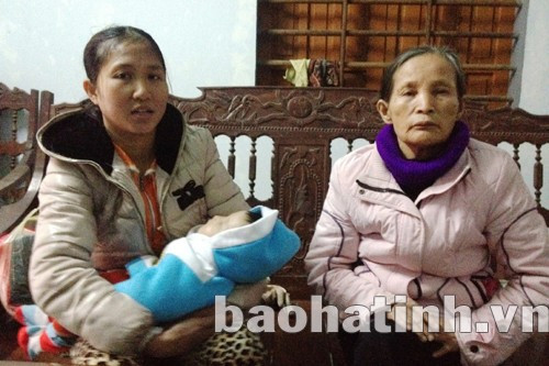 Chị Nguyễn Thị Thủy ôm con nhỏ, ngậm ngùi kể về chồng mình bị Tiệp lừa đang sống chui lủi ở Anggola làm thuê để có tiền về nước - Ảnh: Văn Định