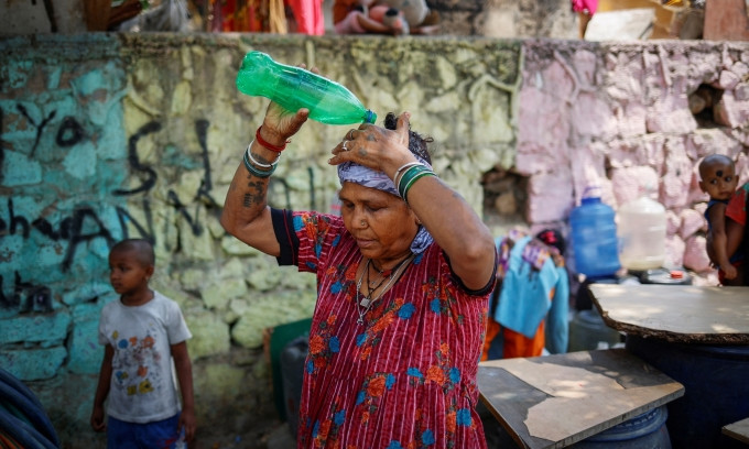 Người phụ nữ dội nước lên đầu để làm mát trong ngày hè oi bức tại New Delhi, Ấn Độ, hôm 21/5. Ảnh: Reuters