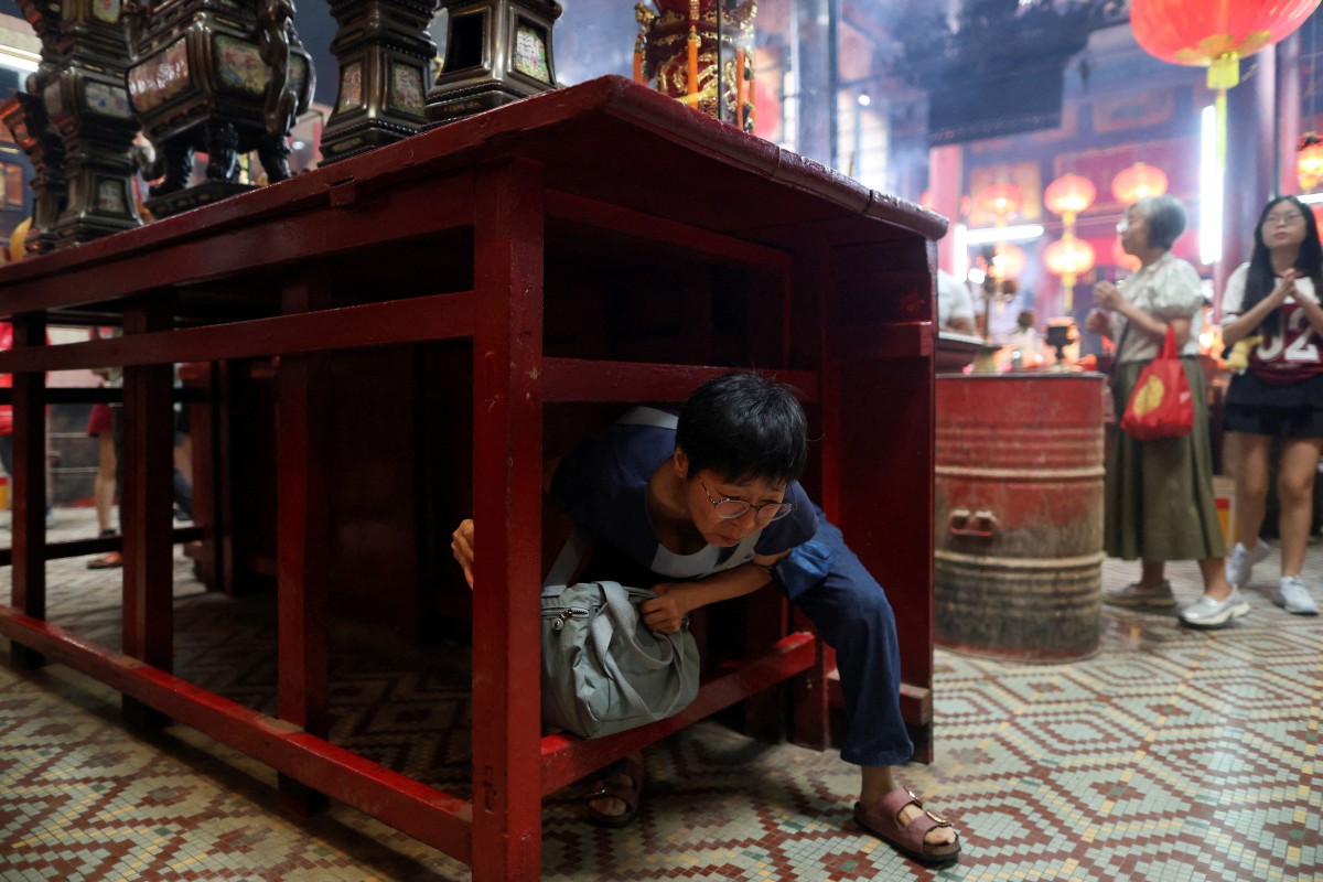 Người dân chui qua gầm bàn thờ nhằm cầu an tại đền Đạo giáo Sin Sze Si Ya ở Kuala Lumpur, thủ đô Malaysia. Hành động "chui qua" mang ý nghĩa vượt qua xui rủi của năm cũ và bước sang năm mới với vận khí tốt hơn. Đây không phải phong tục phổ biến ở Malaysia hay Trung Quốc, mà là nghi thức mang tính địa phương tại ngôi đền này.