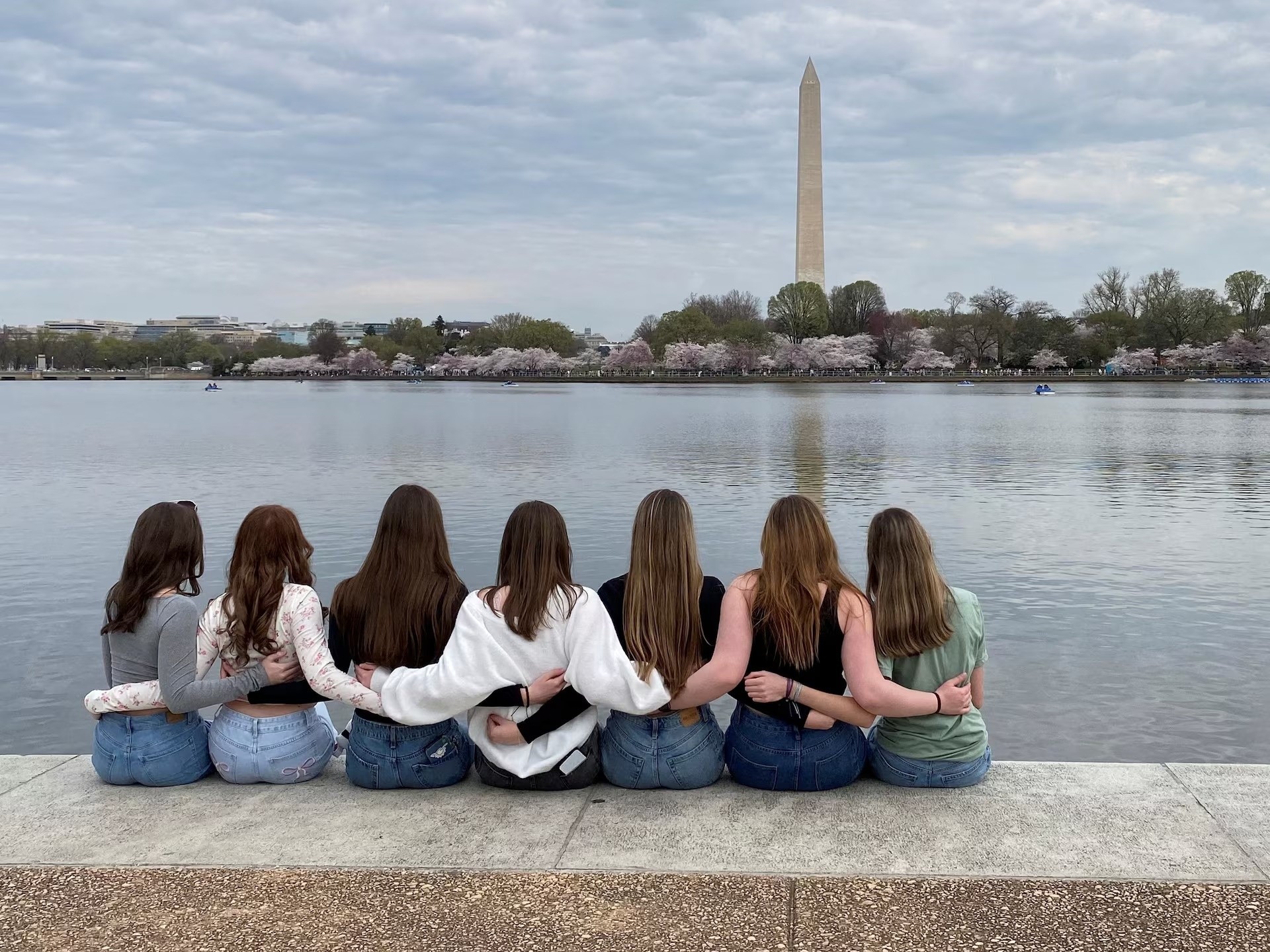 Nhóm bạn ngồi trên bờ Tidal Basin gần Đài tưởng niệm Jefferson vừa ngắm cảnh hoa đào nở vừa chụp ảnh kỷ niệm. Ảnh: Will Dunham/Reuters.