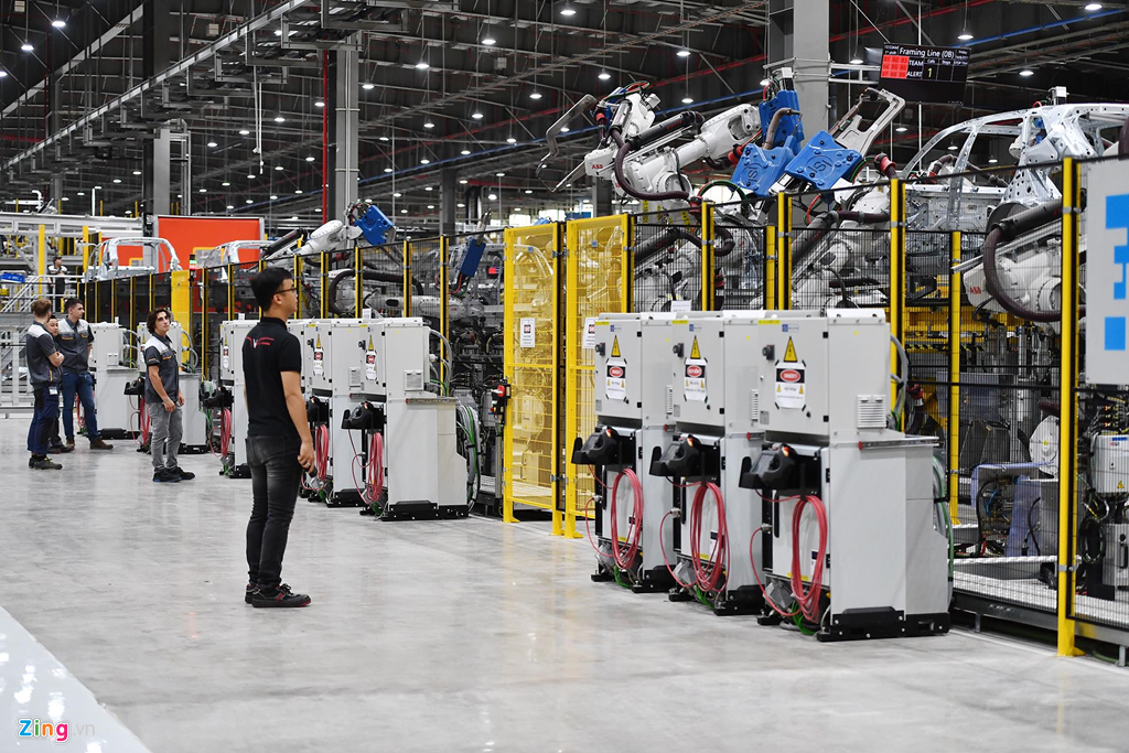 Trong ảnh là xưởng hàn thân xe, diện tích 100.000 m2, được thiết kế và cung ứng dây chuyền bởi các đối tác hàng đầu như FFT, EBZ, HIROTEC, có trang bị khoảng 1.200 robot do ABB sản xuất. Cảnh hối hả sản xuất ôtô bên trong nhà máy VinFast
