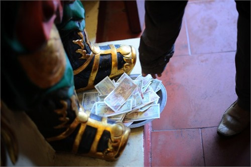 Du khách đi lễ kẹp tiền vào tượng tại Hội Lim (Bắc Ninh) 2014 (ảnh lớn). Tiền lẻ rải khắp nơi ở phủ Tây hồ (Hà Nội). Ảnh: Hải Nguyễn - Giang Huy