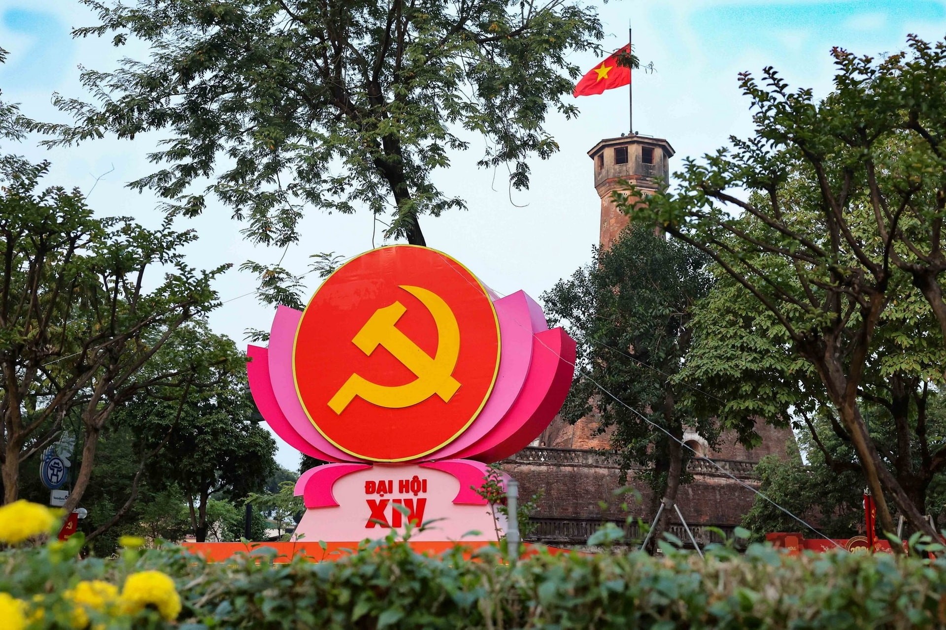 Biểu tượng búa liềm trên đài sen hồng nổi bật trước Cột cờ Hà Nội (khu vực đường Điện Biên Phủ), kết hợp vẻ đẹp lịch sử hào hùng với không khí chính trị trang nghiêm. (Ảnh: Vũ Quang/TTXVN)