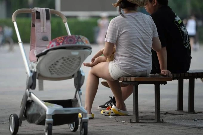 Một cặp vợ chồng Trung Quốc đưa con đi chơi tại công viên. Ảnh: Bloomberg