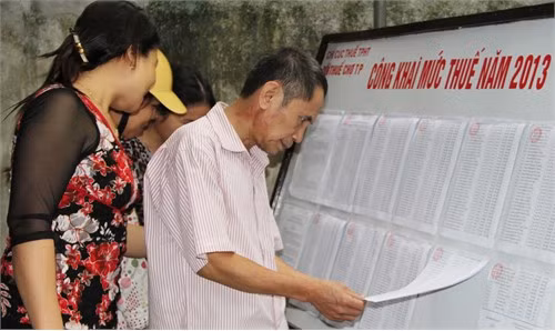 Các tiểu thương chợ thành phố Hà Tĩnh đến xem bảng công khai hạn mức nộp thuế tại Đội Thuế.