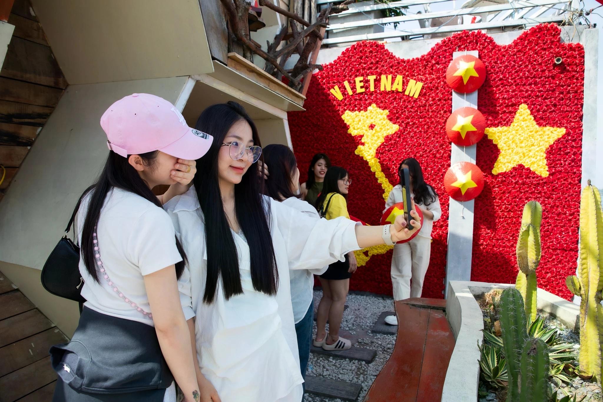 Không chỉ ở khu Ngoại Giao Đoàn, nhiều quán cà phê khác khắp Hà Nội cũng nhanh chóng hòa mình vào không khí lễ hội. Tại Tree Bee - một quán cà phê 4 tầng ở Hồ Tây - giữa trưa nắng vẫn có hàng dài bạn trẻ xếp hàng, chụp ảnh cùng bức tường hoa ghép hình bản đồ Việt Nam. Bức tường sử dụng hơn 3.000 bông hoa với nền đỏ, hình đất nước màu vàng nổi bật giữa trung tâm.