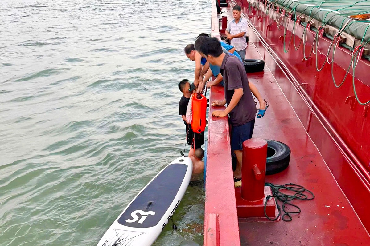Lực lượng cứu hộ đưa 2 bố con anh Nguyễn Thanh Tùng từ thuyền sup lênh đênh 13 giờ trên vùng biển Hà Tĩnh lên tàu vận tải vào sáng 31/7/2025. 1.jpg