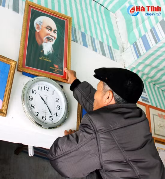 Ông Nguyễn Hữu Đức - Bí thư Chi bộ thôn Phúc Hải lau chùi ảnh Bác chuẩn bị đón năm mới