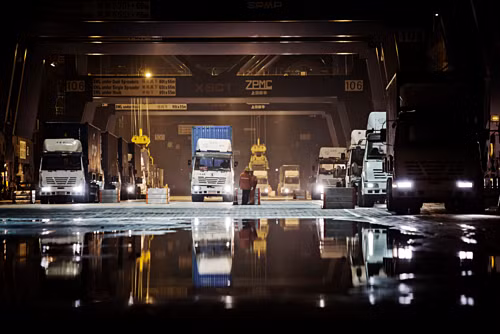 Xe tải chờ nhận hàng ban đêm tại một cảng ở Hạ Môn, Trung Quốc. Ảnh: Bloomberg Kinh tế toàn cầu bên bờ suy thoái vì căng thẳng Mỹ - Trung