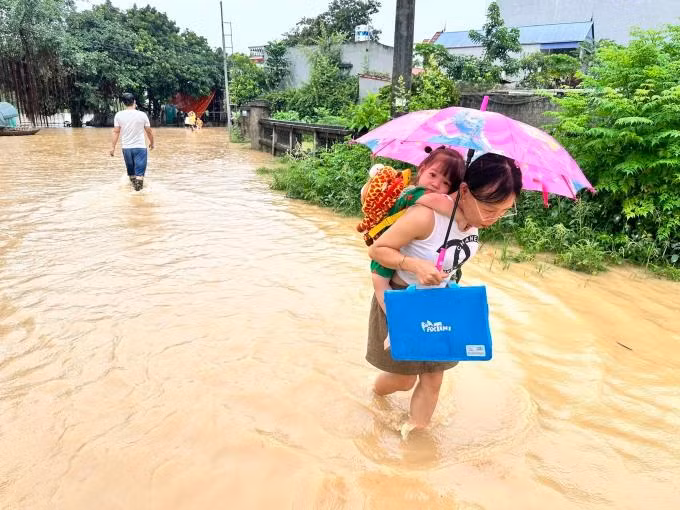 Người dân ngoại thành Hà Nội cõng con qua đường ngập đến trường ngày 25/7. Ảnh: Gia Chính