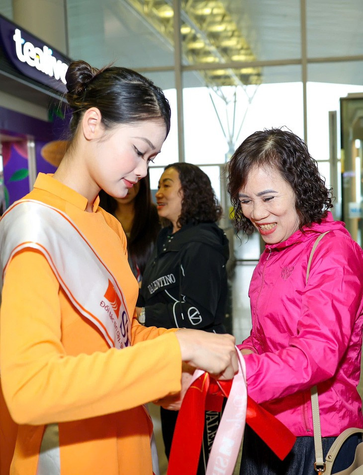 Mẹ của Hoàng Đức đang được một nữ nhân viên đeo một dây băng rôn cổ vũ đội tuyển Việt Nam - Ảnh: NGUYỄN KHÁNH Mẹ của Hoàng Đức đang được một nữ nhân viên đeo một dây băng rôn cổ vũ đội tuyển Việt Nam - Ảnh: NGUYỄN KHÁNH