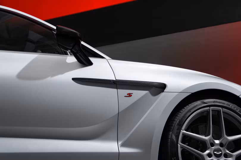 Huy hiệu "S" được đặt phía sau hốc bánh trước. Aston Martin DBX S mang đến 2 gói trang trí ngoại thất tối màu tiêu chuẩn hoặc gói ngoại thất sợi carbon cao cấp.