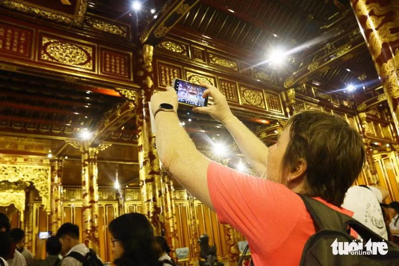 Một du khách nước ngoài thích thú, chụp hình trước vẻ đẹp sang trọng của điện Thái Hòa sau trùng tu - Ảnh: NHẬT LINH