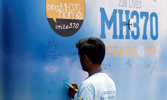 Người đàn ông viết trên bảng tin nhắn cho hành khách trên chuyến bay MH370 mất tích trong sự kiện tưởng niệm thường niên tại Kuala Lumpur, Malaysia, tháng 3/2019. Ảnh: Reuters