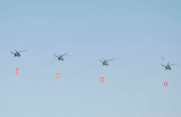 Biên đội máy bay trực thăng mang cờ bay trên bầu trời khu vực tổ chức lễ kỷ niệm. (Ảnh: Thống Nhất/TTXVN)