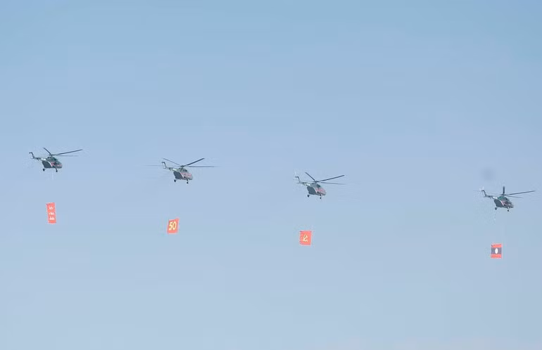 Biên đội máy bay trực thăng mang cờ bay trên bầu trời khu vực tổ chức lễ kỷ niệm. (Ảnh: Thống Nhất/TTXVN)