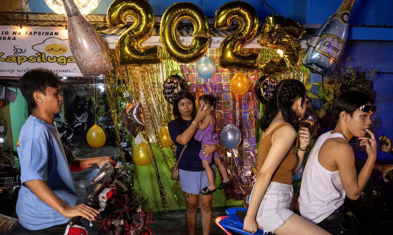 Một người phụ nữ che tai cho đứa trẻ trong lễ mừng năm mới tại một con phố ở thành phố Mandaluyong, Metro Manila, Philippines, ngày 31/12/2024. Ảnh: Eloisa Lopez/Reuters.
