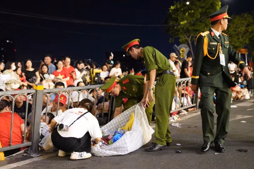 Lực lượng chức năng làm nhiệm vụ đảm bảo an ninh khu vực diễu binh, diễu hành cùng nhóm các bạn trẻ thu gom rác thải, nhắc nhở người dân cùng giữ vệ sinh chung. Ảnh: Linh Huỳnh.