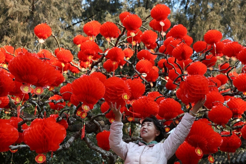 Một người phụ nữ chụp ảnh với những chiếc đèn lồng đỏ trang trí tại công viên ở Bắc Kinh, Trung Quốc trước thềm năm mới. Ảnh: Reuters.