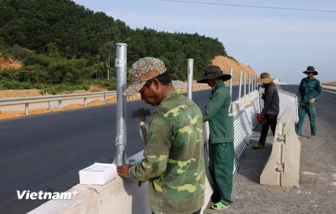 Công nhân lắp đặt dải phân cách và lưới chống chói tại Dự án cao tốc Quảng Ngãi-Hoài Nhơn. (Ảnh: Quốc Khánh/Vietnam+)
