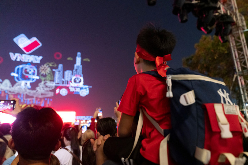 Một bạn nhỏ được bố cõng trên cổ để có thể nhìn ngắm màn trình diễn từ trên cao. Ảnh: Linh Huỳnh.