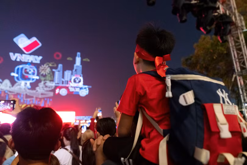 Một bạn nhỏ được bố cõng trên cổ để có thể nhìn ngắm màn trình diễn từ trên cao. Ảnh: Linh Huỳnh.