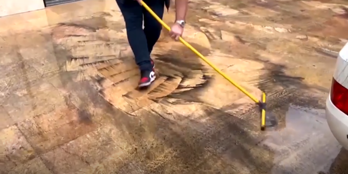 Nhân viên vệ sinh lau vết dầu sau cơn mưa trước cửa văn phòng WHO tại Tehran, ngày 8/3. Ảnh: Reuters