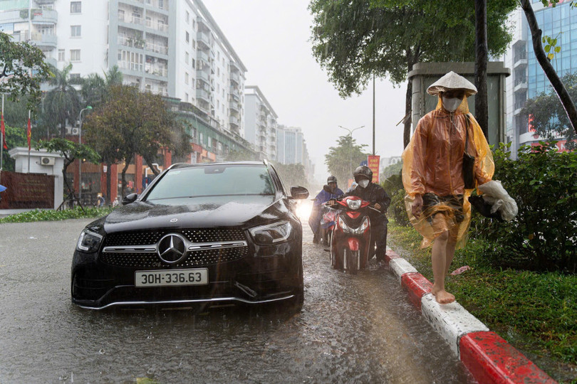 Lề đường ngập sâu, nhiều phương tiện phải di chuyển men theo dải phân cách ở giữa. Dù vậy, không ít người vẫn lựa chọn dắt bộ để tránh bị nước vào động cơ. Ảnh: Trần Hiền.