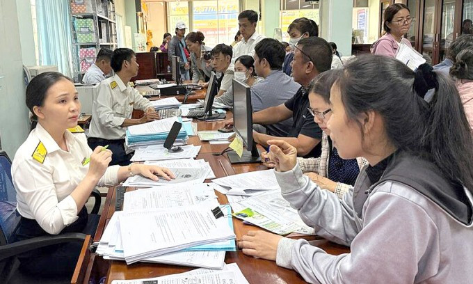 Cán bộ thuế hướng dẫn thủ tục cho người dân. Ảnh: Cục Thuế