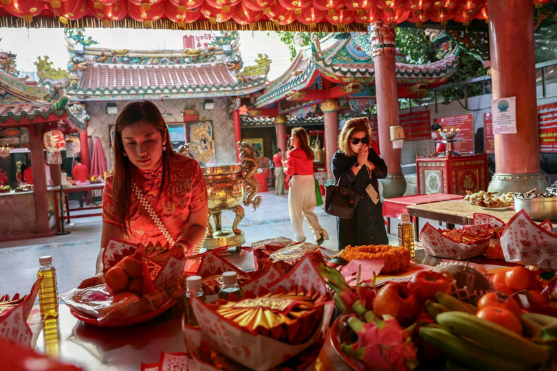 Người phụ nữ dâng lễ vật lên các vị thần trong nghi lễ thờ cúng truyền thống vào đêm giao thừa Tết Nguyên đán tại khu phố Chinatown, Bangkok, Thái Lan ngày 28/1. Ảnh: Reuters.