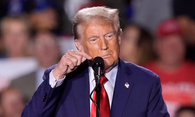 Ông Trump gõ vào mic trong cuộc mít tinh ở Detroit, Michigan, hôm 18/10. Ảnh: AP