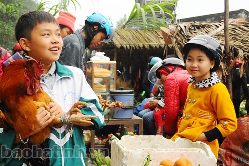 Ôm chú gà trống trên tay, cậu bé hớn hở vì được phụ giúp mẹ đi chợ Tết