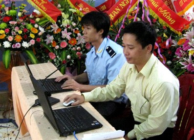 Cán bộ kỹ thuật hải quan và đại diện doanh nghiệp thao tác thí điểm khai, nhận điện tử trên máy