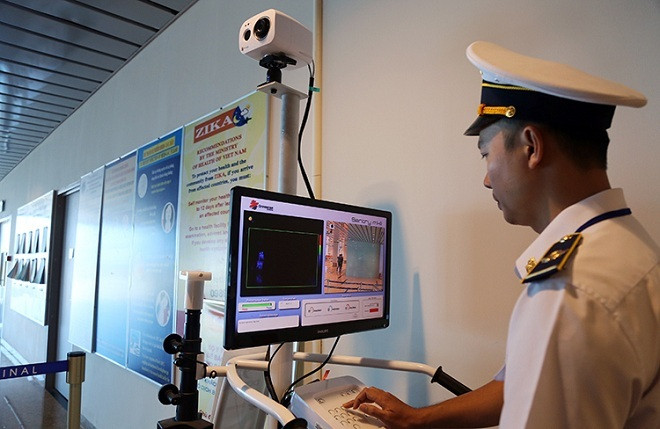 Nhân viên của Trung tâm Kiểm dịch y tế quốc tế theo dõi thân nhiệt khách nhập cảnh, chiều 13/1. Ảnh: Xuân Ngọc Hai người từ Vũ Hán - Trung Quốc nhập cảnh Việt Nam bị sốt