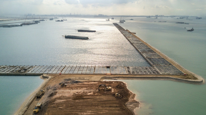 Phần lớn diện tích của Singapore cao không quá 15 m so với mực nước biển. Vị trí này mang lại lo lắng cho các nhà hoạch định chính sách trong bối cảnh nước biển dâng lên vì biến đổi khí hậu. Các nhà khoa học dự đoán đến năm 2020, mực nước biển sẽ tăng lên 1,8 m trong khi bão dữ sẽ đập vào bờ nhiều hơn. Tại Singapore, những cung đường ven biển đang được tăng độ cao, nhà ga sân bay mới sẽ được xây cao hơn mực nước biển 5 m. Trong ảnh, một góc khác của công trình siêu cảng đang được xây dựng. cong cuoc lap bien mo dat cua singapore