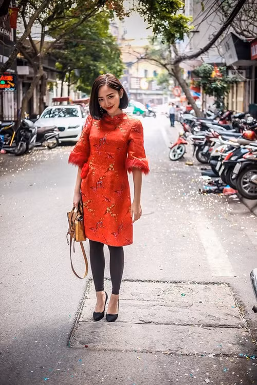 Áo dài cách điệu in họa tiết mai vàng cùng điểm nhấn lông vũ mềm cho cổ tay được Tóc Tiên kết hợp với quần legging, túi ánh kim vàng gold.