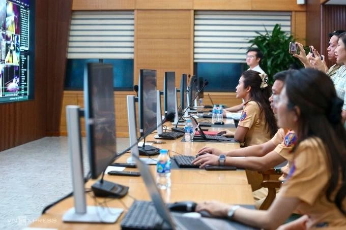 Hàng chục CSGT làm việc thông qua máy tính và màn hình lớn tại Trung tâm Thông tin chỉ huy của Cục Cảnh sát giao thông. Ảnh: Việt An