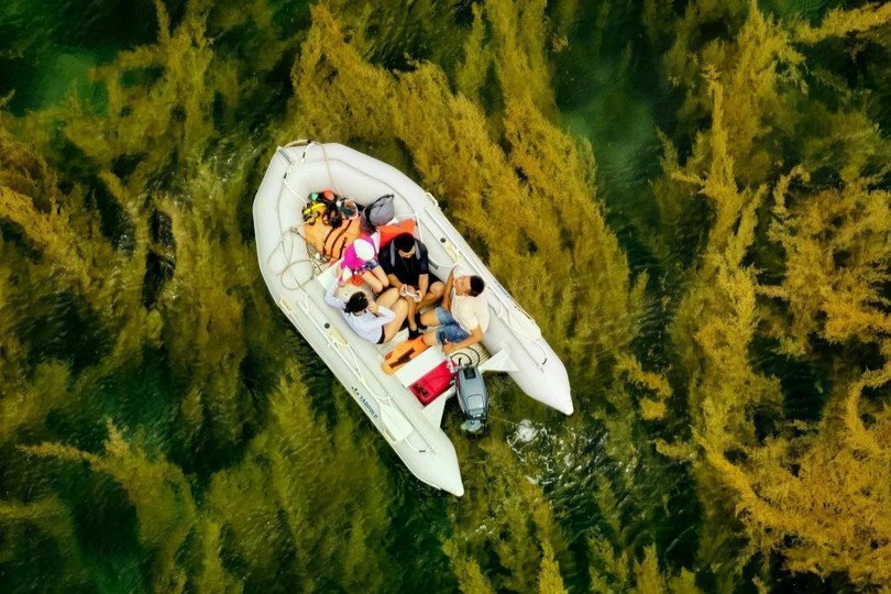 Hiếu Linh (áo đen) ngồi trên ca nô, sử dụng drone để tác nghiệp tại vịnh Đầm Tre, Côn Đảo, tháng 5/2025.