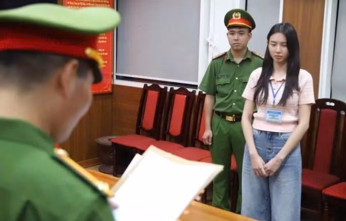 Hoa hậu Thùy Tiên (phải) nghe cảnh sát đọc lệnh khởi tố, bắt tạm giam, ngày 19/5. Ảnh: Bộ Công an