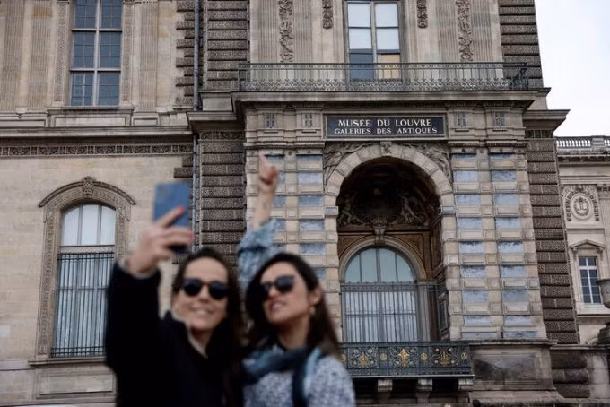 Du khách check in khung cửa sổ nơi nhóm trộm đã đột nhập vào bảo tàng Lourve: Ảnh: Reuters