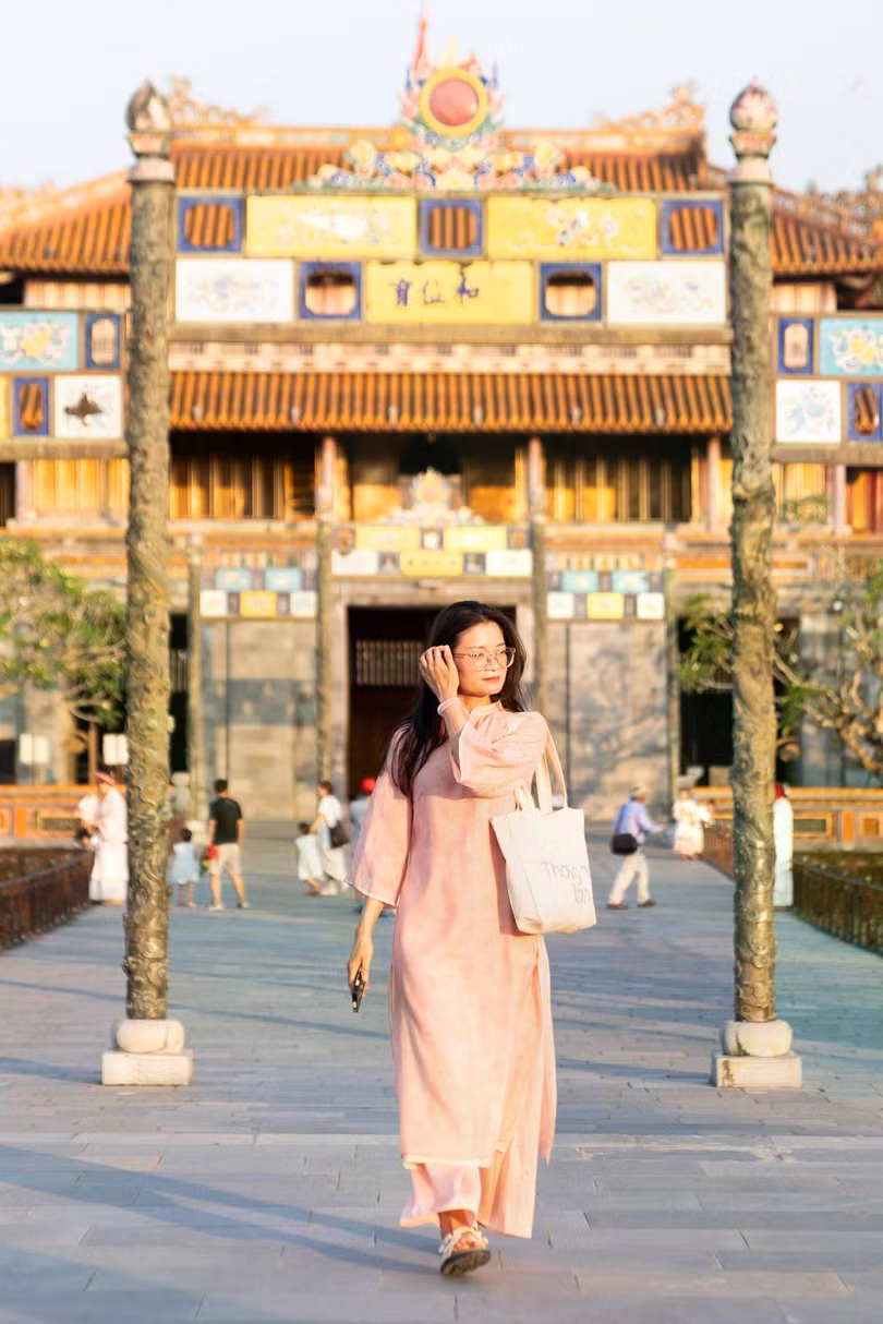 Du khách diện áo dài rảo bước trong Đại nội Huế dưới ánh nắng hè rực rỡ. Ảnh: Linh Huỳnh.