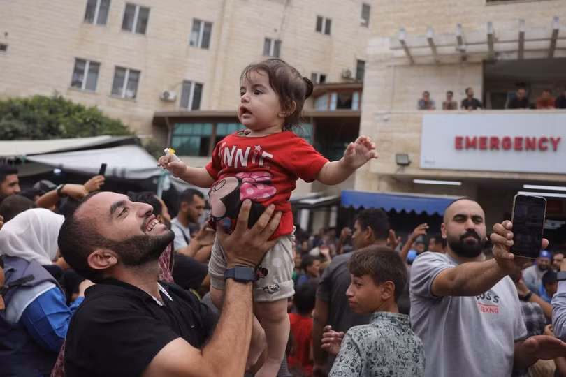 Người cha bế con gái lên cao, hòa chung niềm vui với những người xung quanh bên ngoài bệnh viện Shuhada al-Aqsa ở Deir al-Balah, miền trung Dải Gaza.