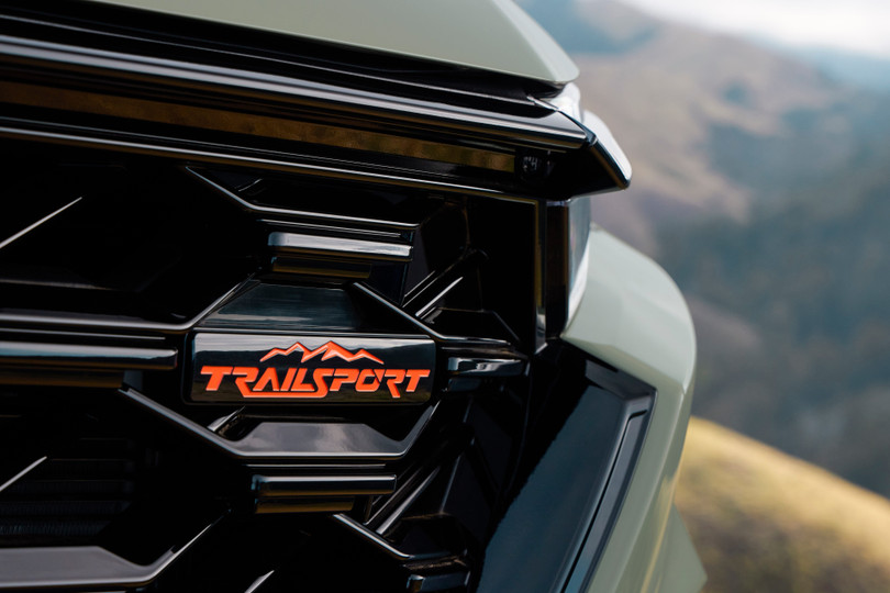 Nhiều chi tiết được sơn tối màu như lưới tản nhiệt dạng mắt cáo, ốp tai gương ngoại thất, tay nắm cửa... Logo TrailSport được đính kèm tại lưới tản nhiệt và cửa khoang hành lý.