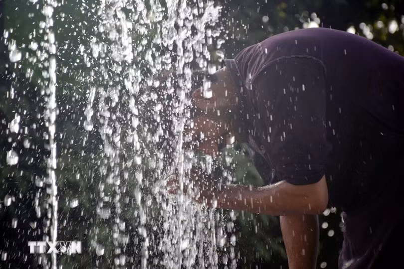 Người dân làm mát bên vòi phun nước ở Lahore khi sóng nhiệt bao trùm Pakistan, ngày 22/5/2024. (Ảnh: THX/TTXVN)