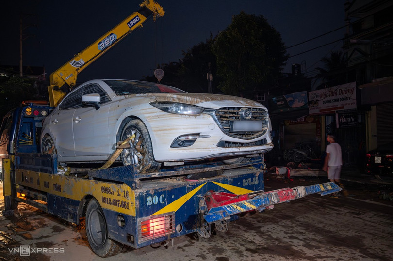 Một trong số hàng trăm ôtô ngập nước được đưa lên xe cứu hộ. Vết bùn đất bám rõ trên thân xe.