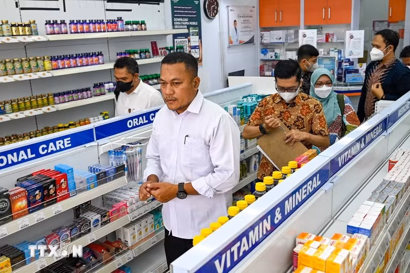 Cảnh sát kiểm tra các sản phẩm siro ho tại một hiệu thuốc ở Banda Aceh, Indonesia. (Ảnh: AFP/TTXVN)